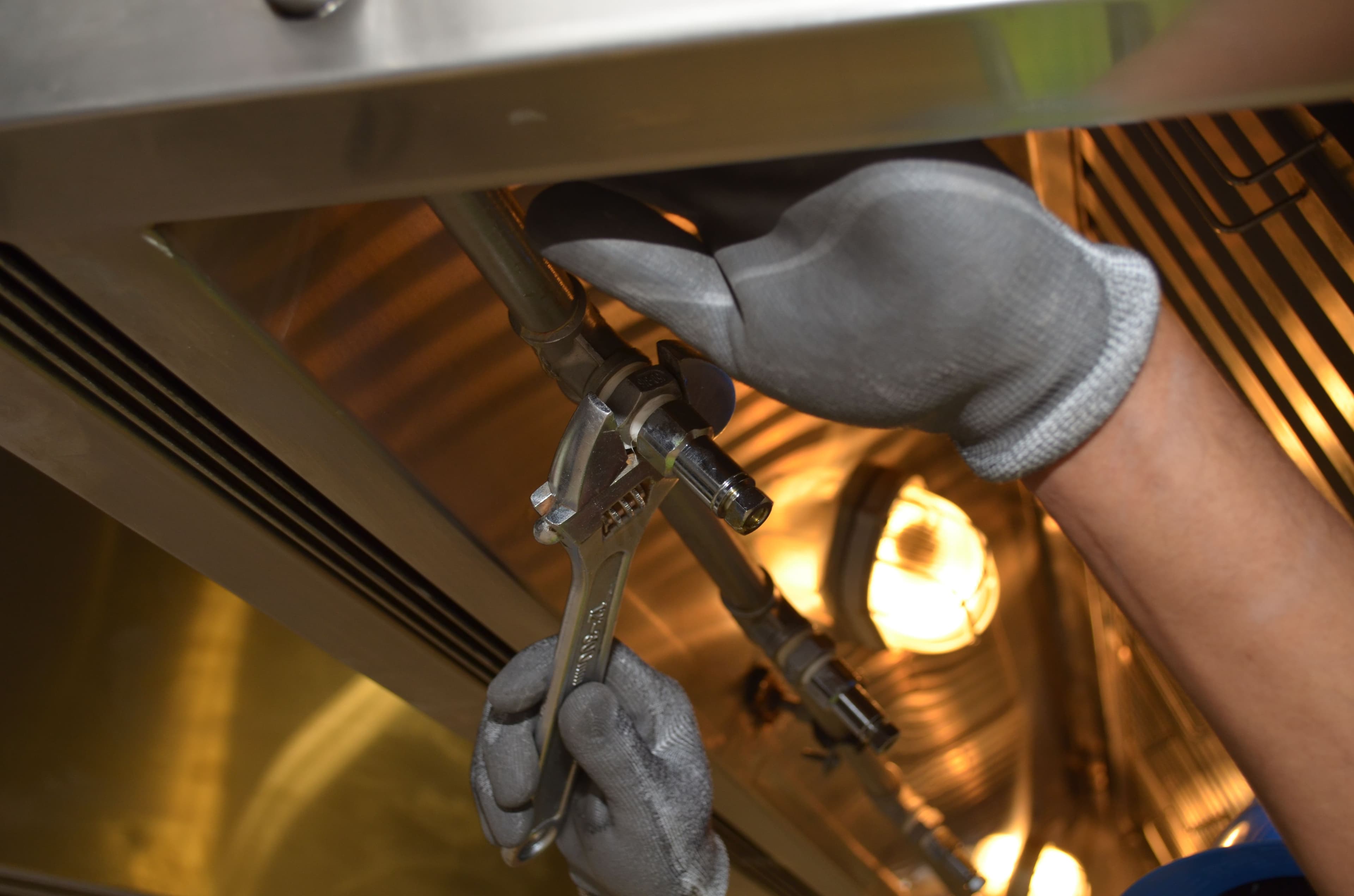 Representative photograph of a gloved technician using an adjustable wrench on mechanical equipment.